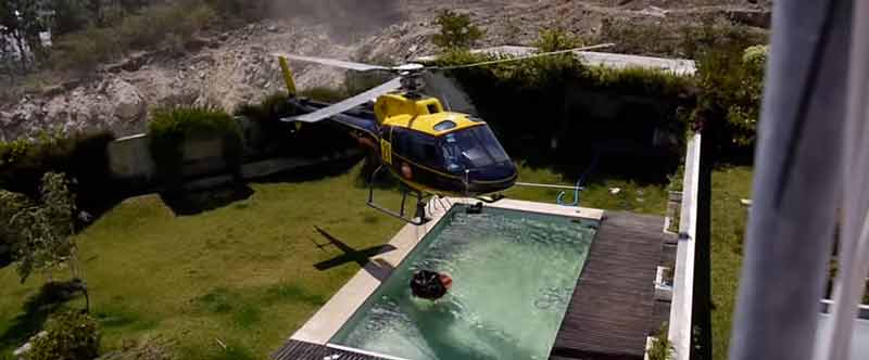 Helicóptero cogiendo agua de una piscina para apagar incendios