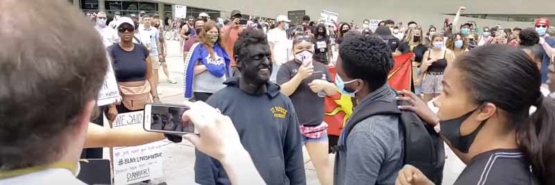 Un hombre pintado totalmente de negro es arrestado en una manifestación