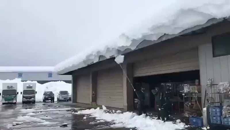 Quitando la nieve del tejado de un almacén