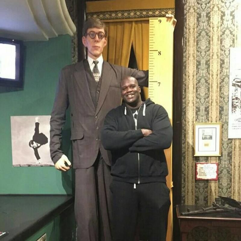 Shaquille O'Neal junto a una estatua de Robert Wadlow, el humano más alto de la historia