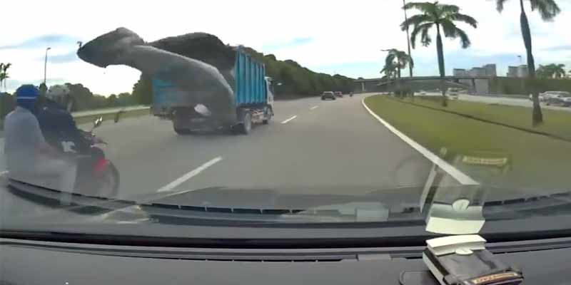 La lona de un camión se suelta y tira a un motorista