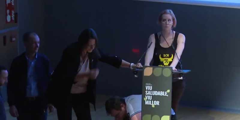 Una activista se pega al atril en un acto político en Barcelona