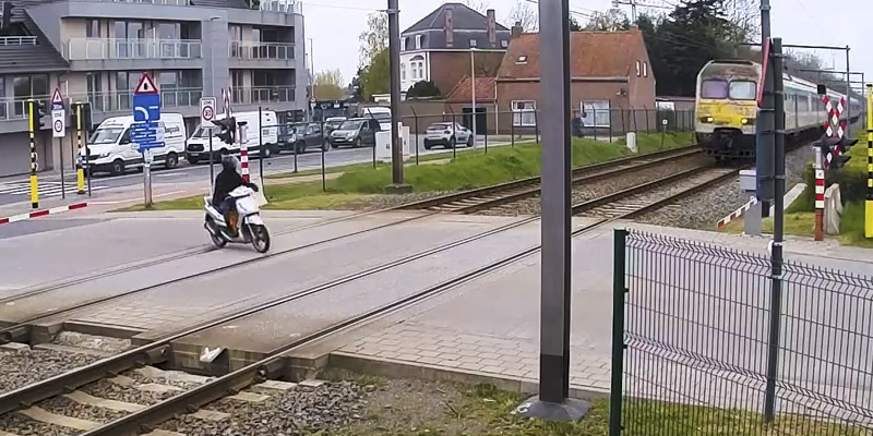 El de la scooter casi es arrollado por el tren