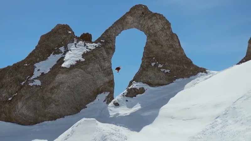 Saltando esquiando a través del arco de piedra natural de la Aiguille Pierced